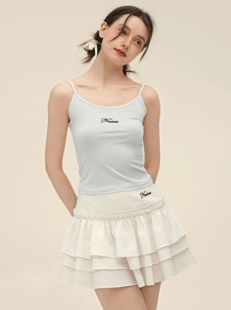 Woman in a light blue camisole and white ruffle skirt with pigtails