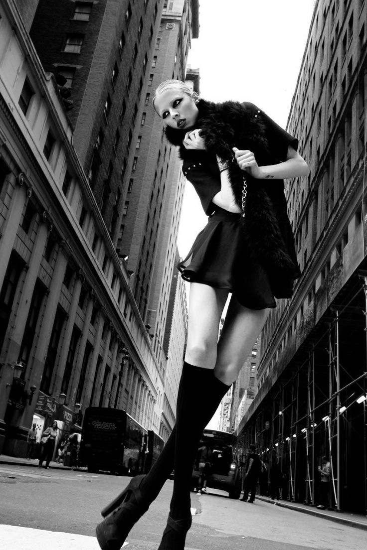 Woman in a fur vest and short skirt posing on a city street