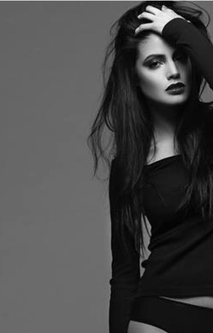 Woman with long dark hair and dark lipstick in a black top and underwear