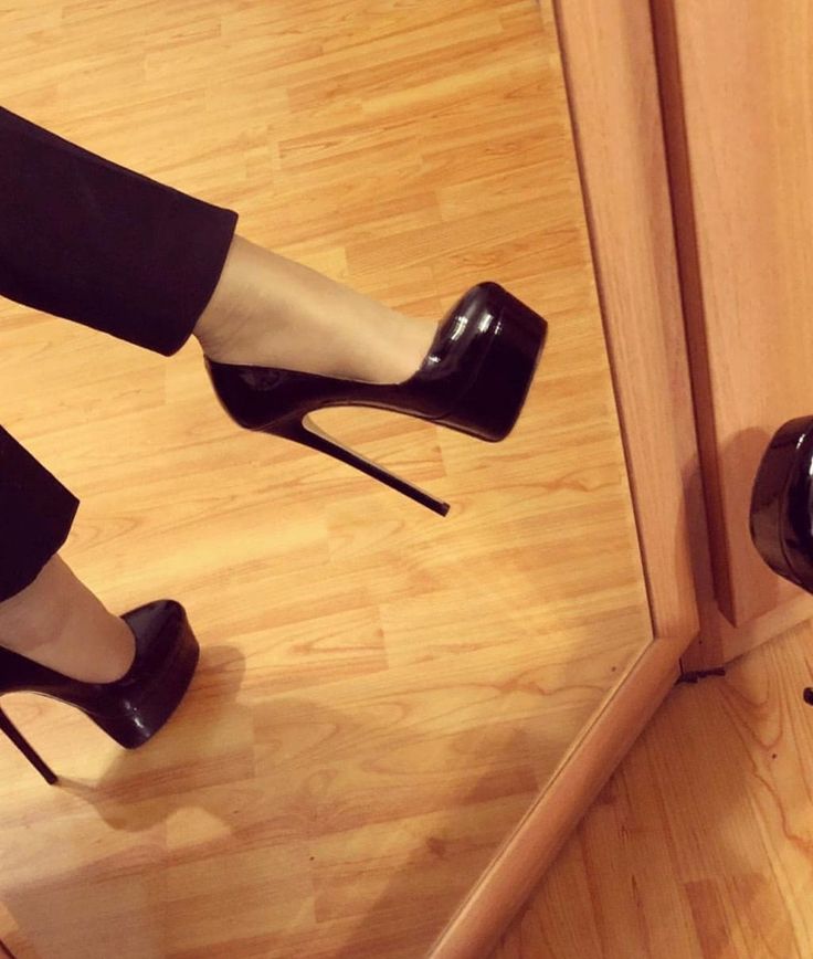 Person wearing black high heels with platform soles on a wooden floor