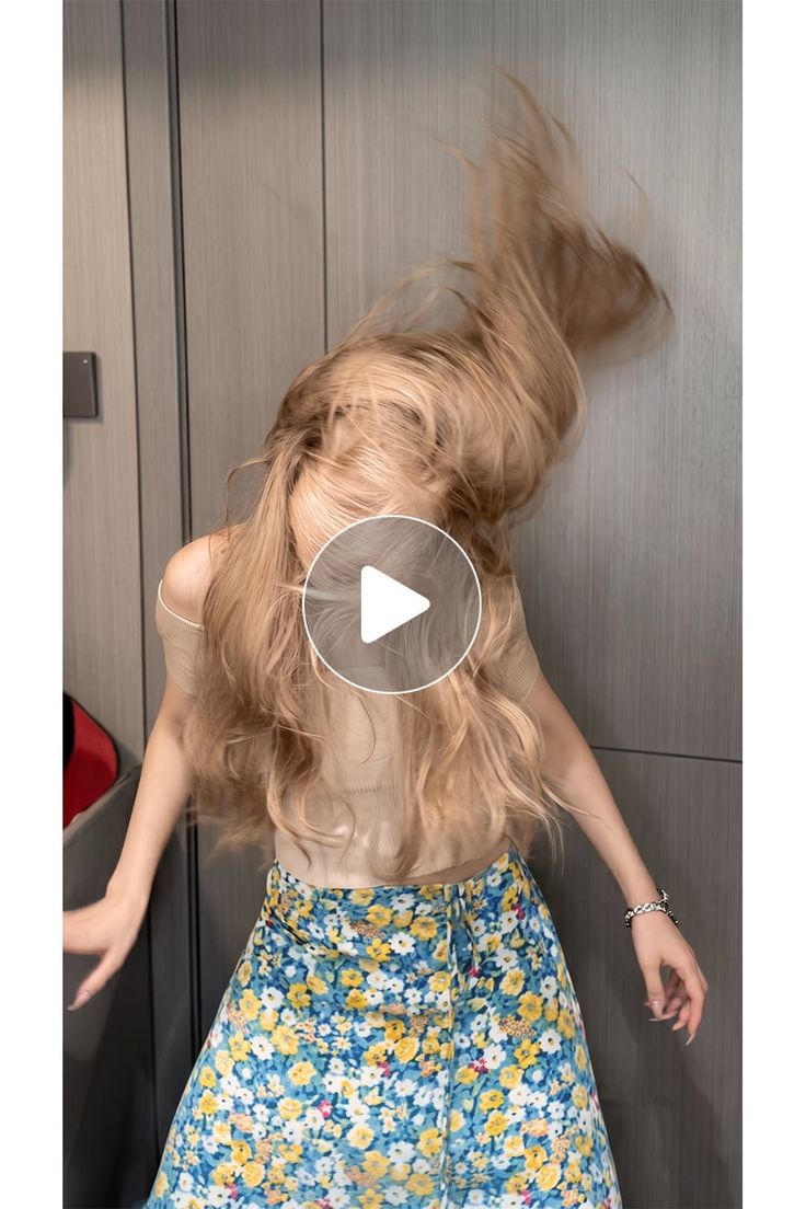 Woman with long blonde hair in motion, wearing a floral skirt and off-shoulder top