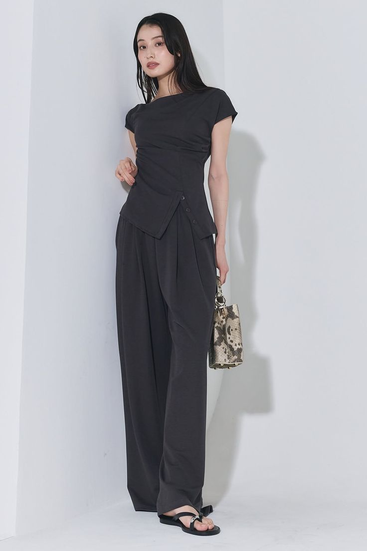 Woman with long black hair wearing an asymmetrical top and wide-leg pants