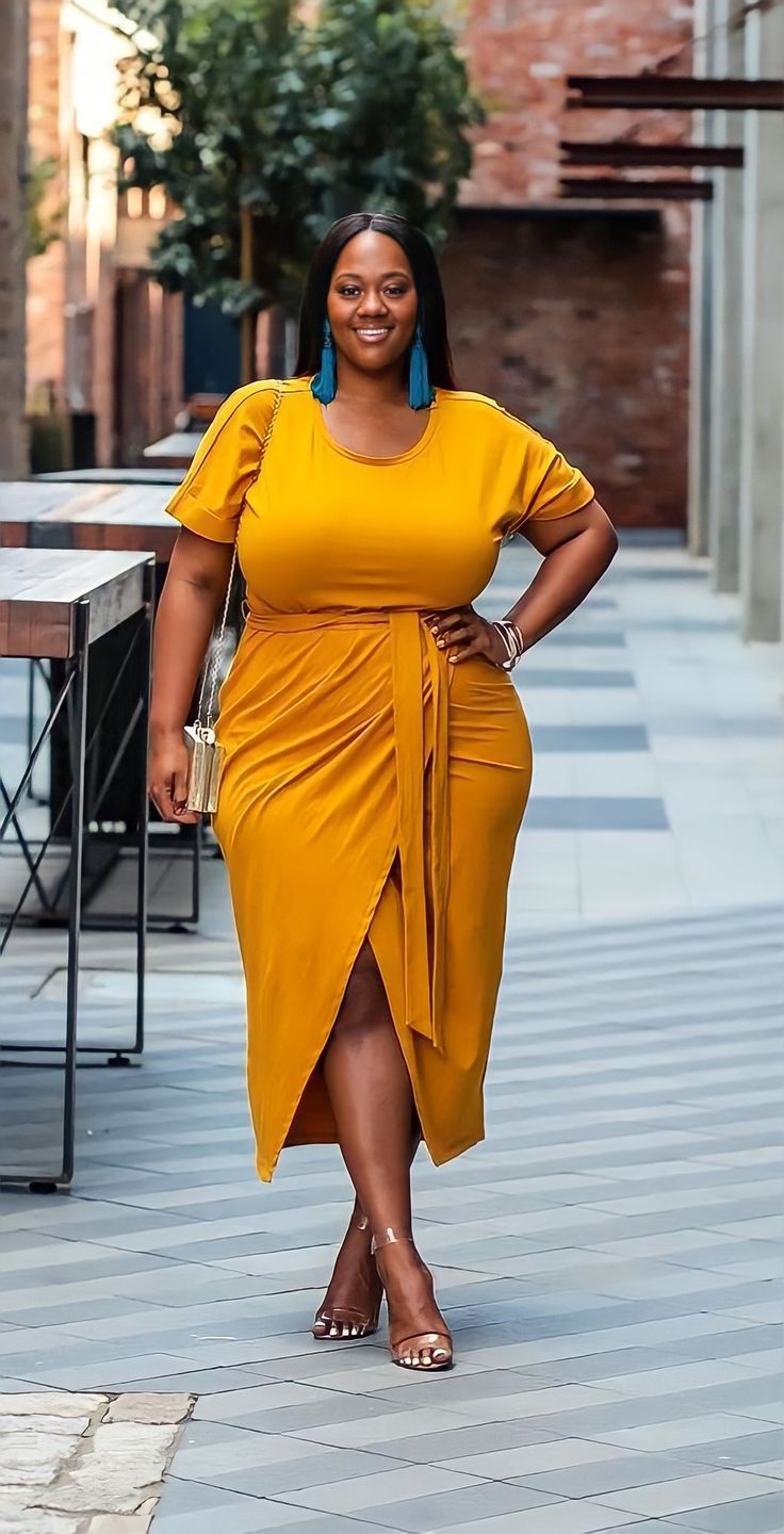 Woman in a yellow dress and blue earrings posing outdoors