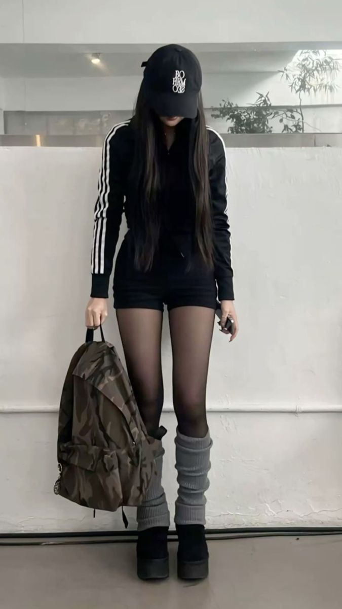 Person in black athletic wear, cap, and leg warmers holding a camouflage backpack