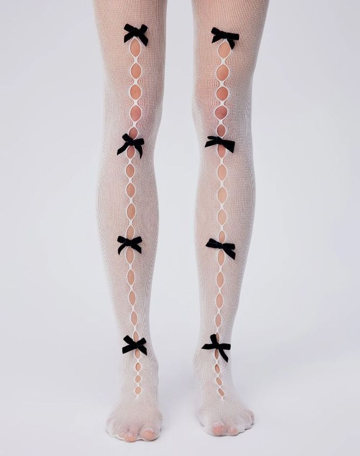 Legs wearing white fishnet stockings with black bows on a white background