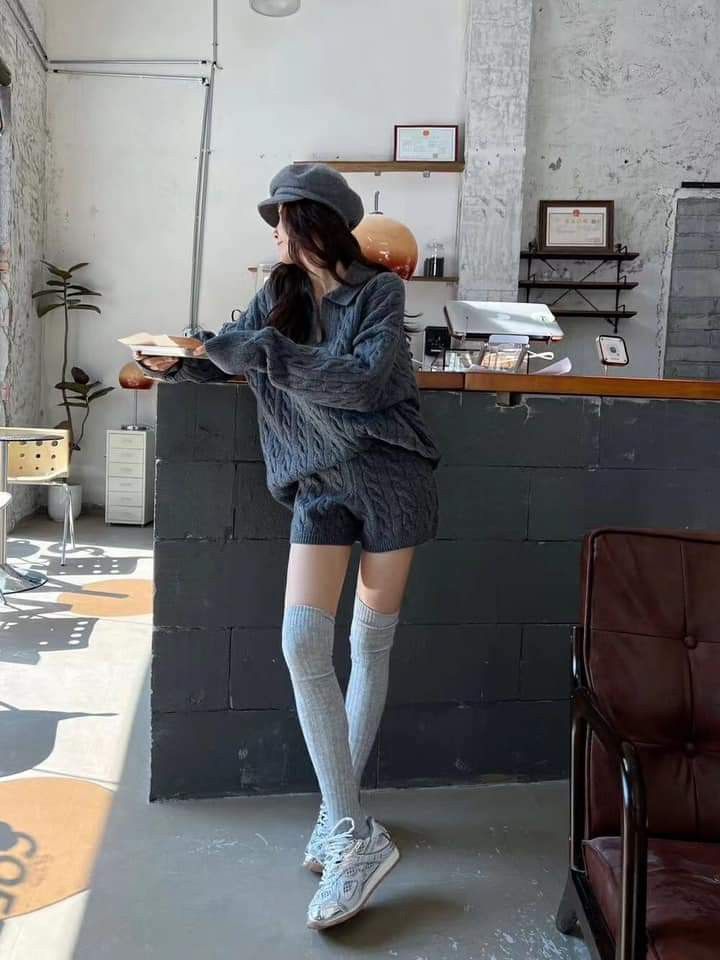 Woman in a grey knitted set, beret, and thigh-high socks in an indoor setting