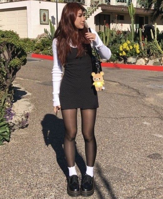 Woman in a black dress and white long sleeve shirt outdoors on a sunny day