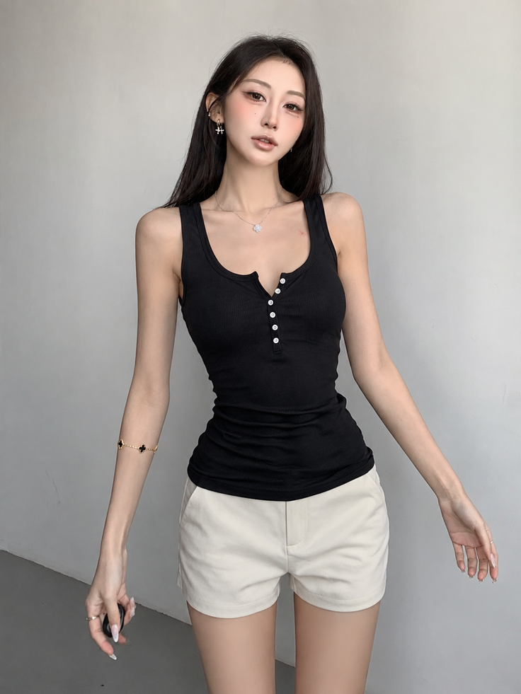 Woman in a black tank top and white shorts posing indoors