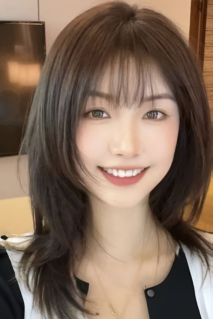 Woman with medium brown hair and bangs smiling at the camera
