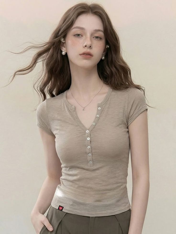 Woman with long wavy hair and freckles wearing a v-neck shirt and pearl earrings