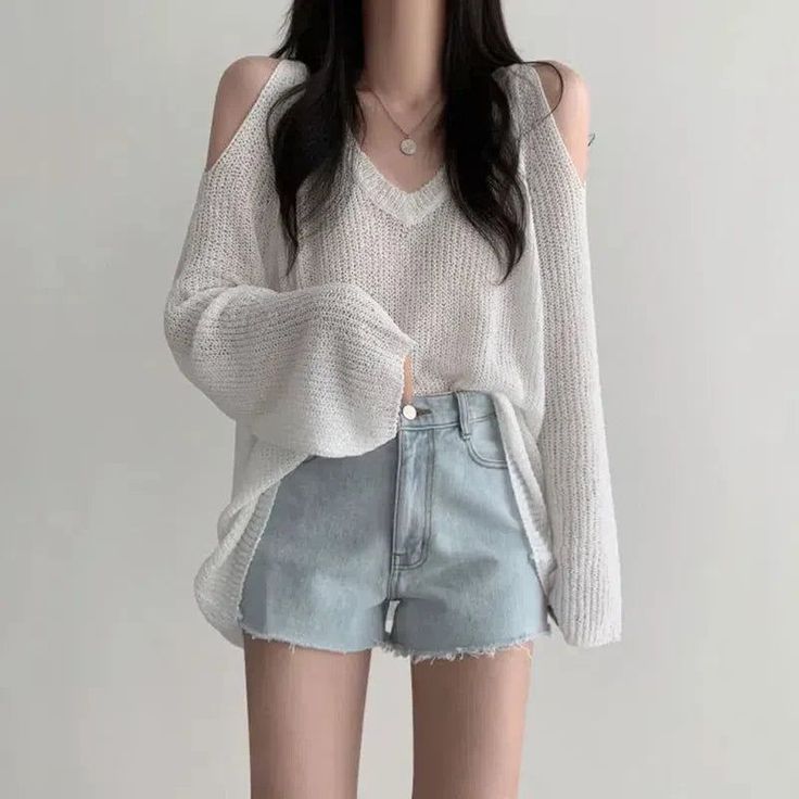 Person in a white off-shoulder sweater and denim shorts