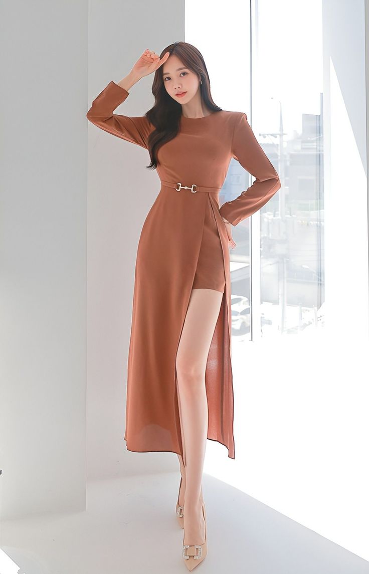 Woman in a long brown dress with a high slit and high heels indoors