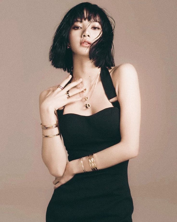 Woman with short black hair wearing a black dress and jewelry in a studio