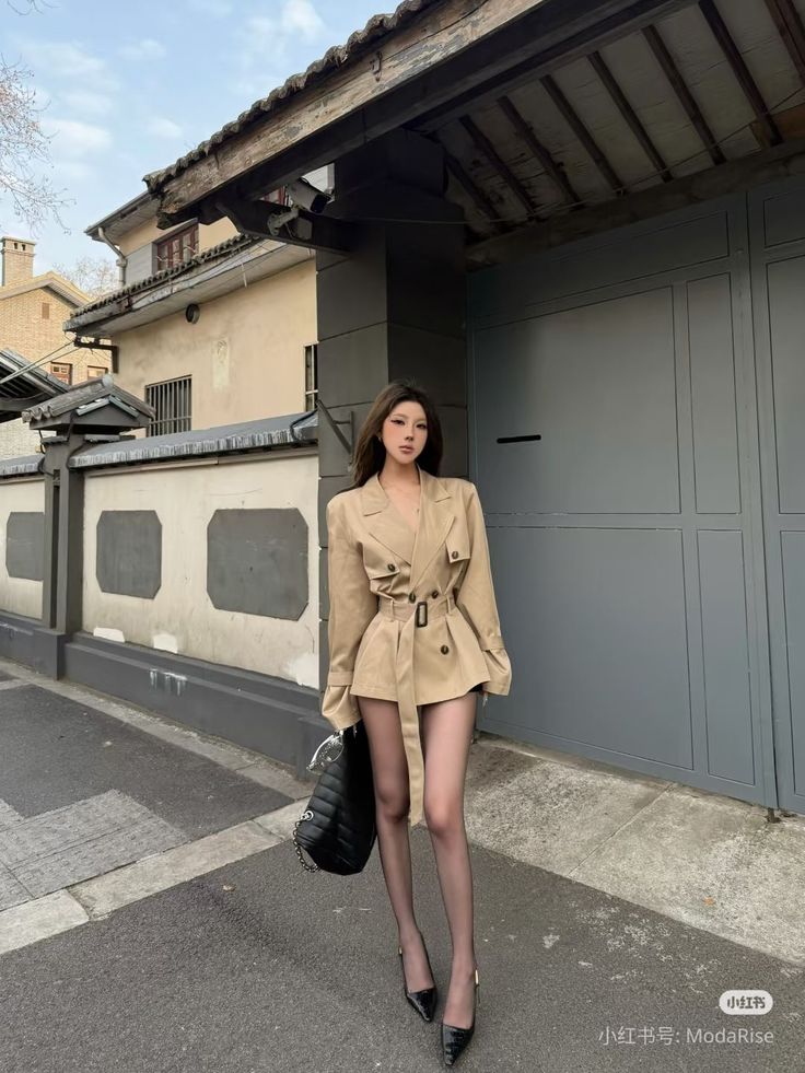 Woman in a beige trench coat and black tights posing outdoors