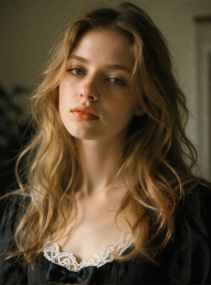 Woman with long wavy hair and blue eyes wearing a black top with lace trim