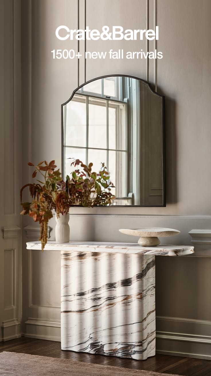Marble console table with a mirror and plant arrangement in an indoor setting