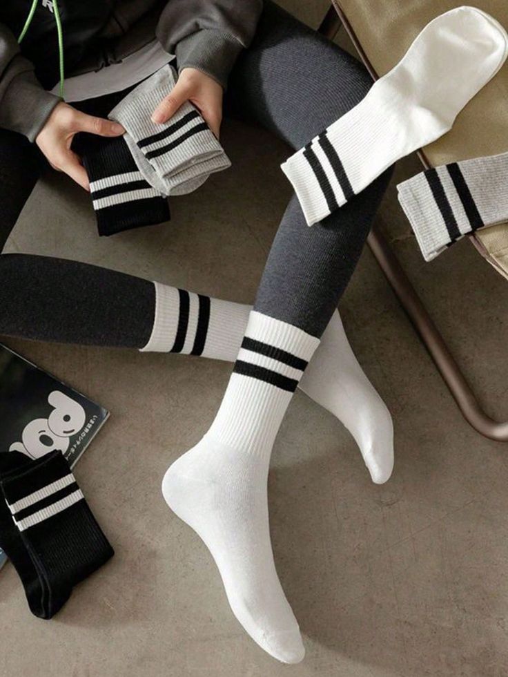 Person wearing gray leggings and white striped socks, holding more socks