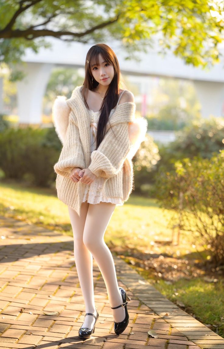 Woman in a white dress and knitted cardigan outdoors during golden hour
