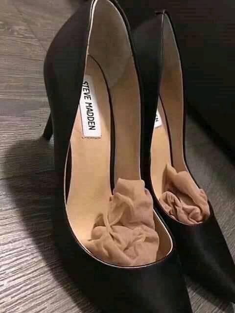 Pair of black high heels with tissue paper inside on a wooden floor