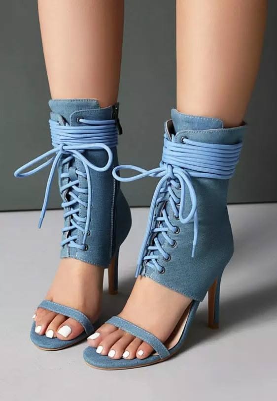 Close up of feet wearing light blue denim lace-up high heels with white nail polish