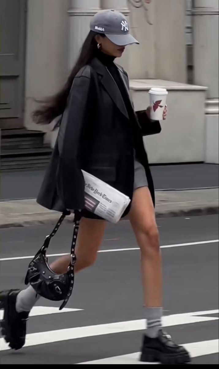 Woman in a black blazer and mini skirt walking across a crosswalk