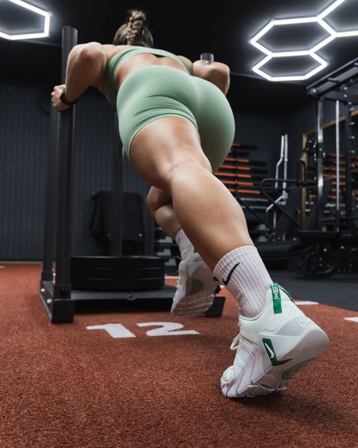 Muscular person in athletic wear pushing a sled in a gym