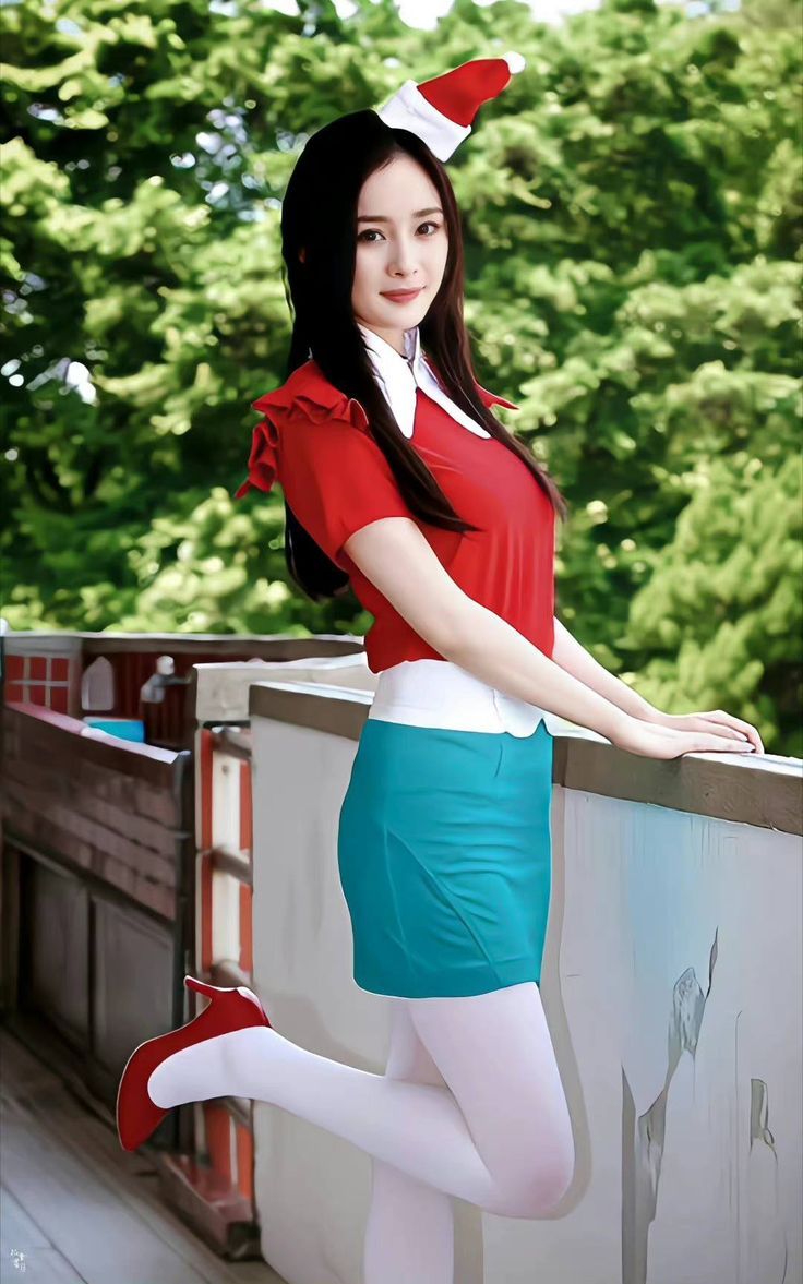 Woman in a red top, teal skirt, and santa hat posing outdoors