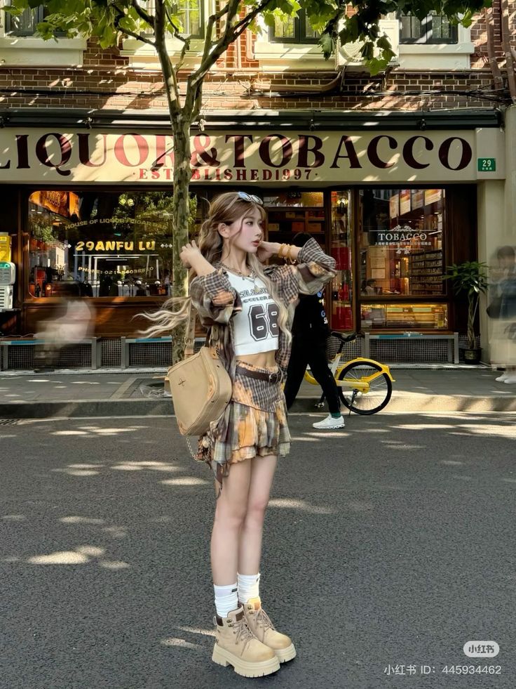 Woman in a plaid skirt and crop top standing on a street in front of a store