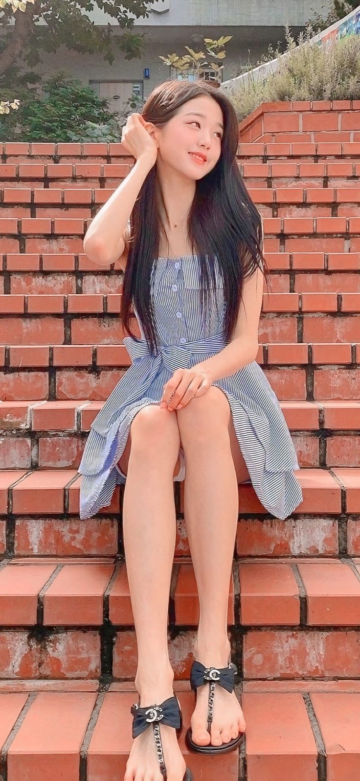 Woman in a striped dress sitting on brick stairs outdoors