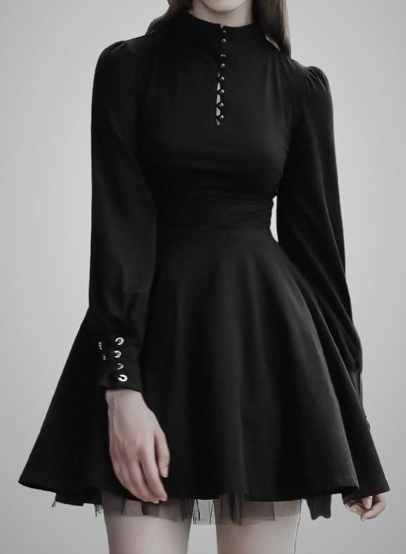 Woman in a black long-sleeved dress with a high collar and eyelet details