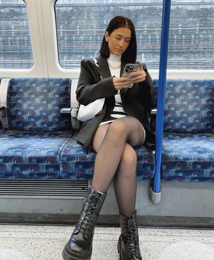 Woman in a black blazer and mini skirt sitting on a subway train