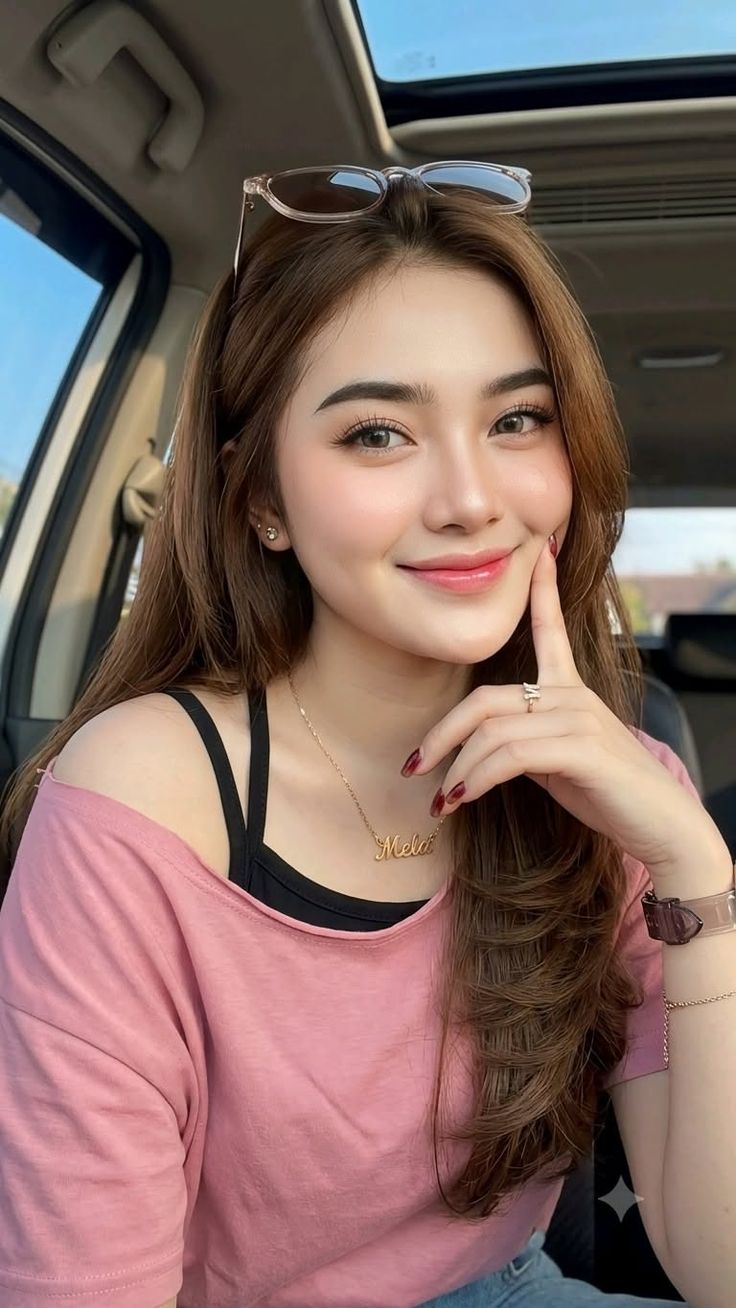 Woman with long brown hair and a pink shirt in a car interior