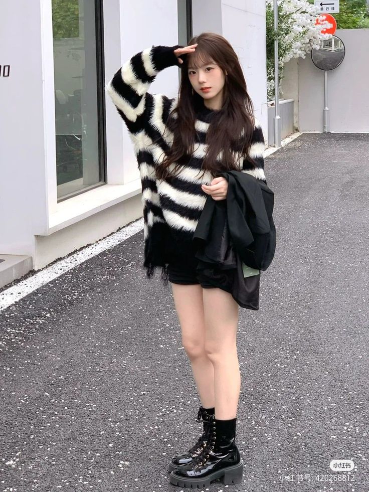 Woman in a striped sweater and black shorts with combat boots outdoors