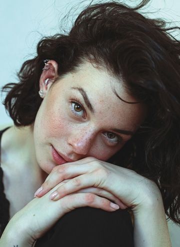 Woman with dark hair and freckles looking at the camera