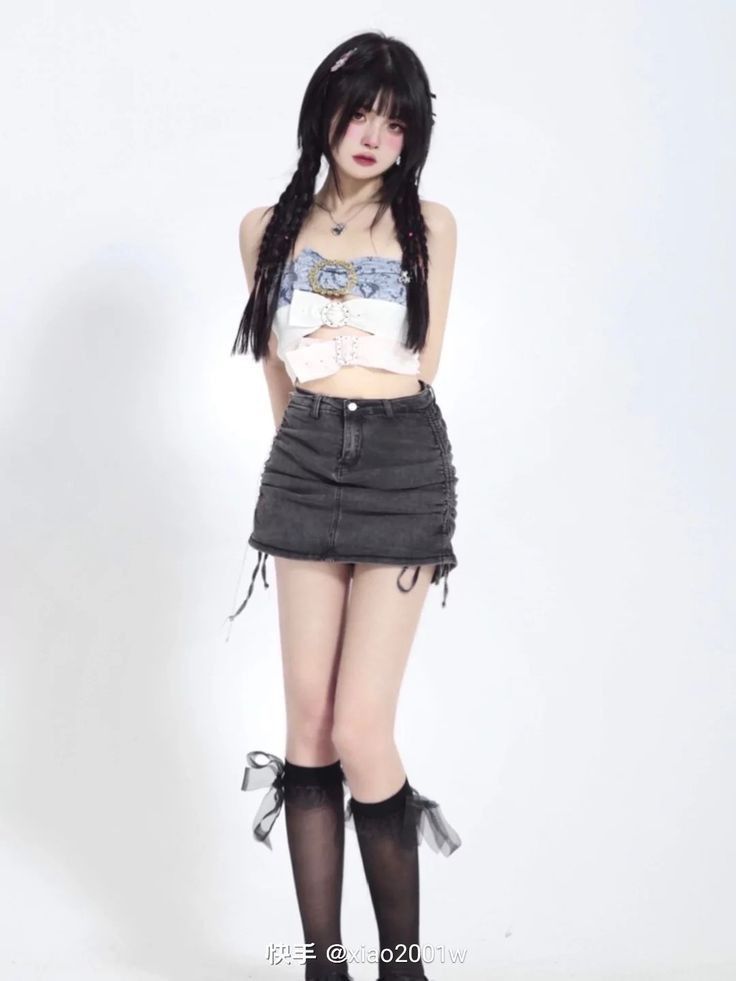 Woman with long braids wearing a crop top and denim skirt with knee-high socks