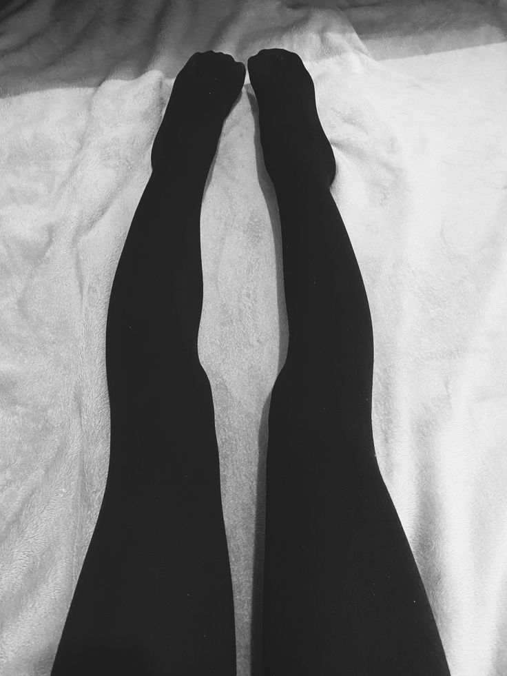 Legs in black tights on a textured white surface in monochrome