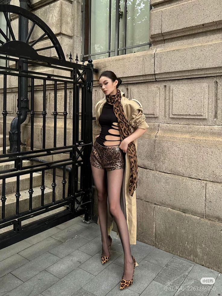 Woman in a cut out top and leopard print shorts with a trench coat