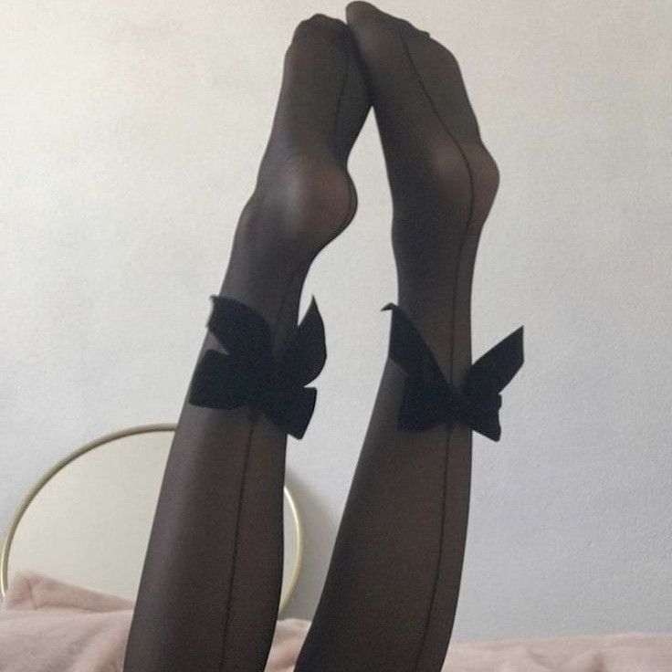 Legs in black seamed stockings with bows, posed indoors