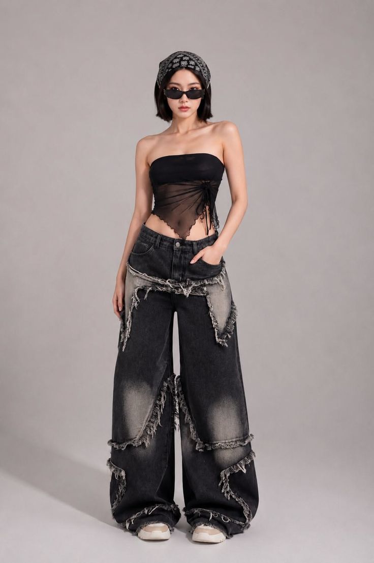 Woman in a sheer top, distressed jeans, bandana, and sunglasses posing in a studio