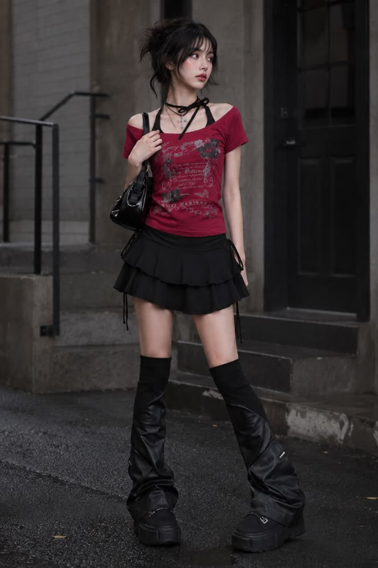 Woman with dark hair wearing a red top and black mini skirt outdoors