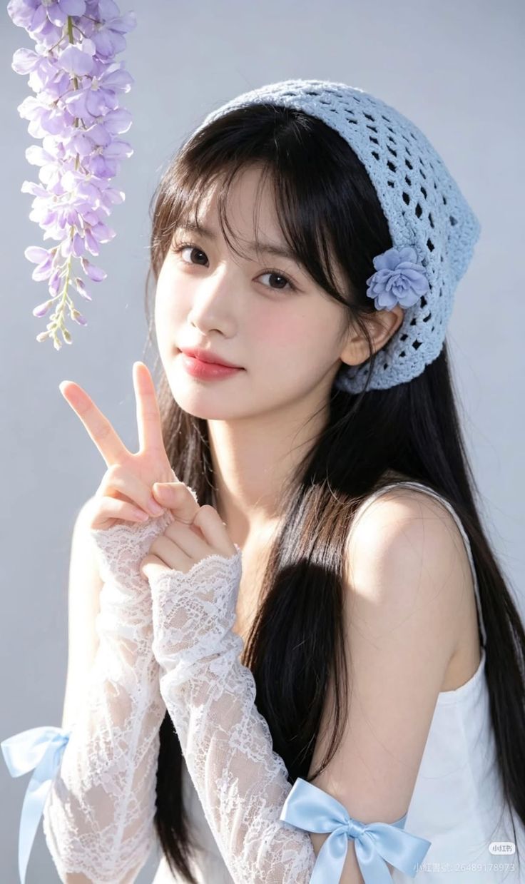 Woman with long black hair wearing a blue crochet bandana and lace gloves, making a peace sign