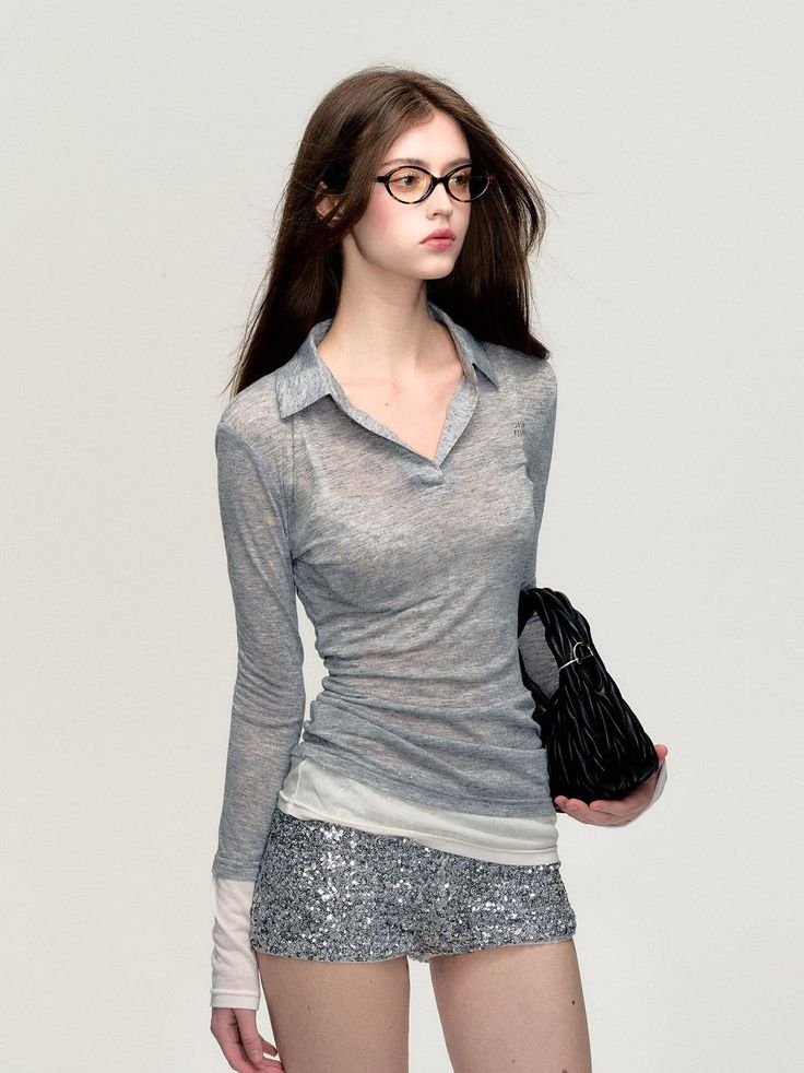 Woman with long hair and glasses wearing a sheer top and sequin shorts