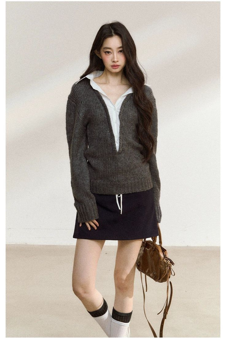 Woman with long dark hair wearing a knitted sweater, mini skirt, and knee-high socks