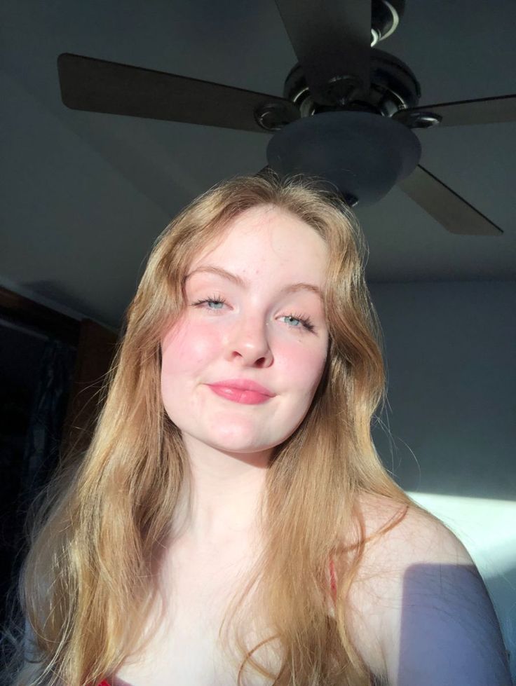 Young woman with long blonde hair and blue eyes indoors with soft lighting