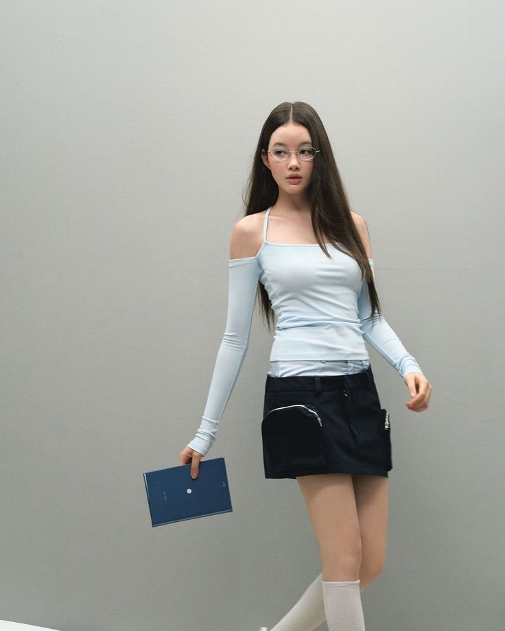 Woman with long hair and glasses wearing a mini skirt and off-shoulder top