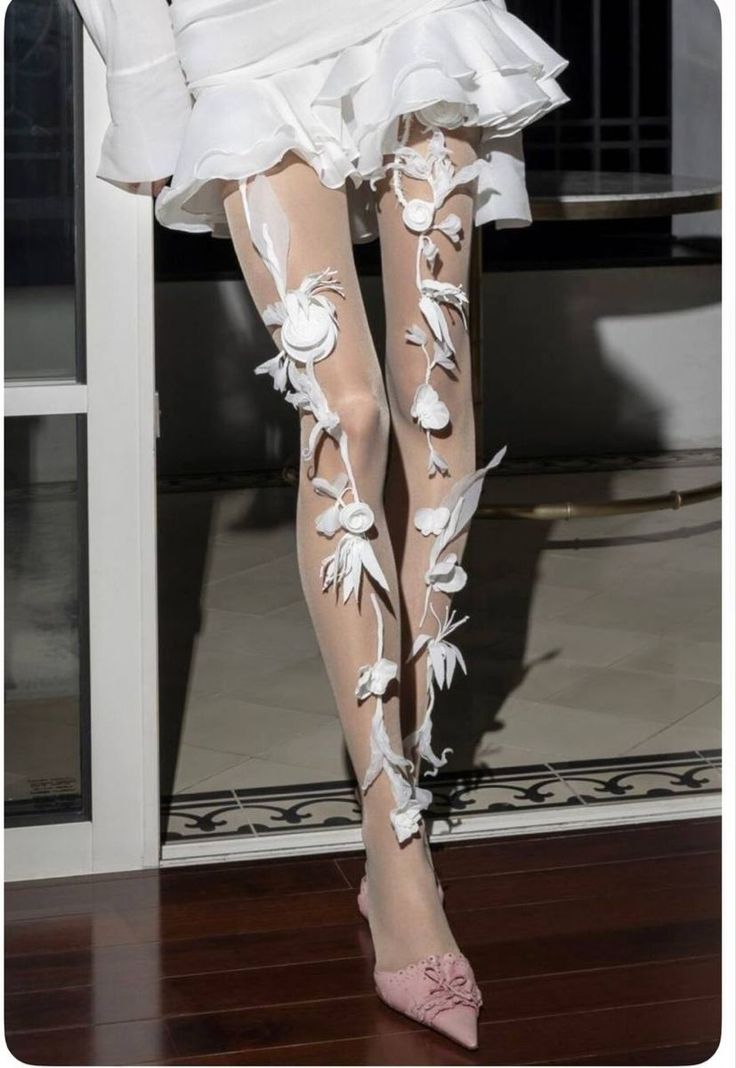 Person in a white dress with sheer floral stockings and pink shoes