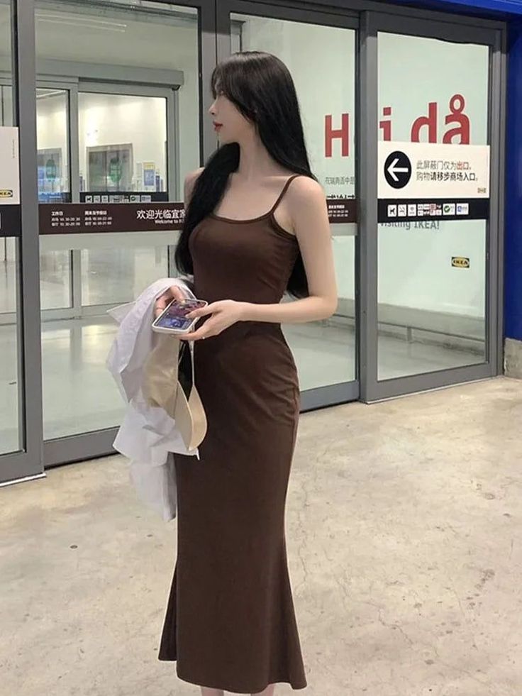 Woman in a brown spaghetti strap dress standing indoors