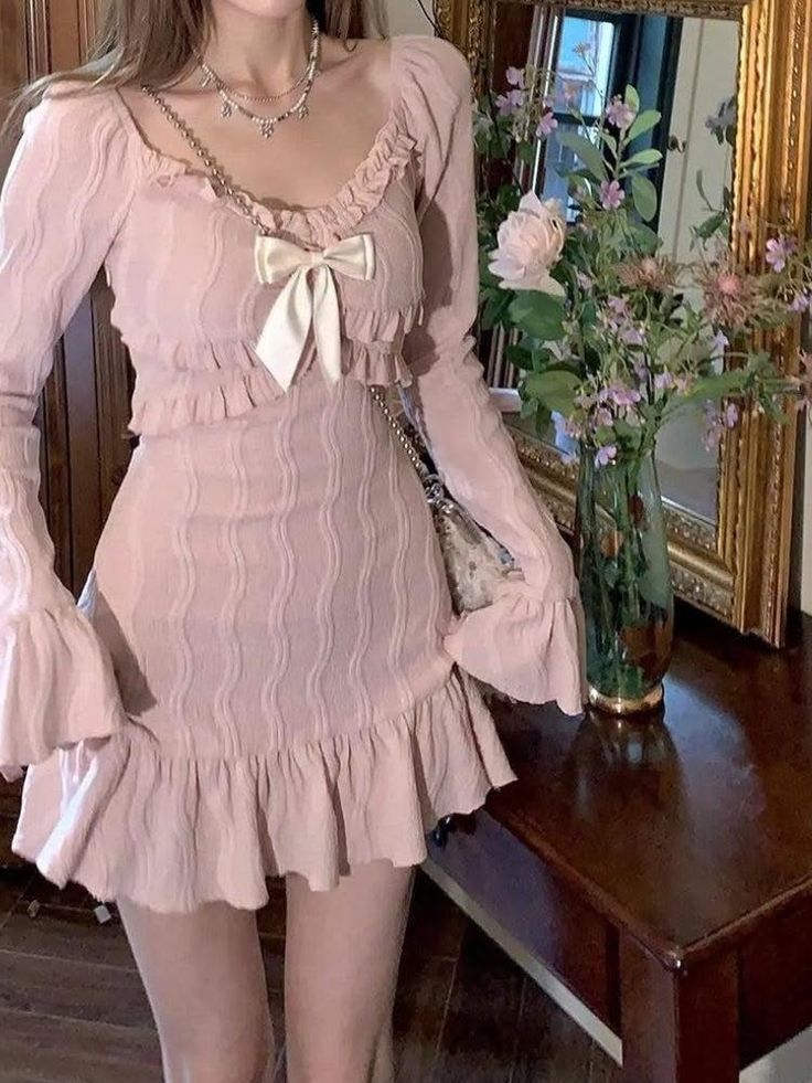 Woman in a pink ruffle dress with a bow and jewelry indoors