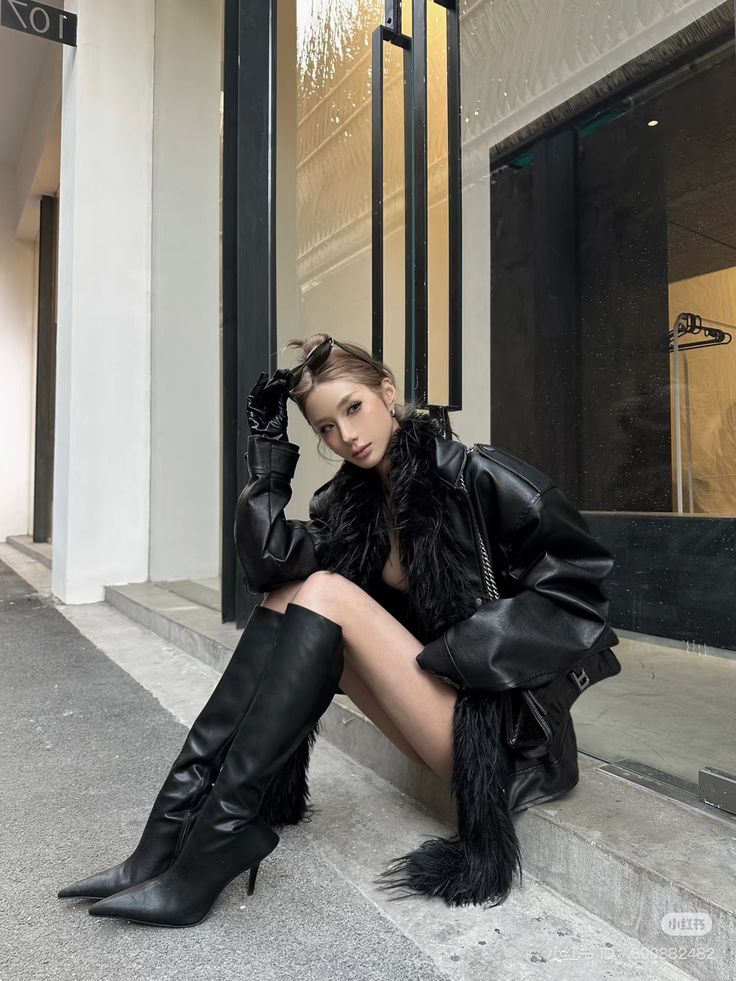 Woman in a leather jacket and thigh-high boots sitting outdoors