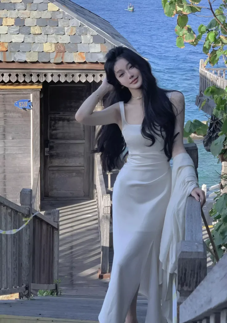 Woman in a white dress on wooden stairs overlooking the ocean